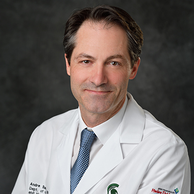 A headshot of Andre Bachmann in a white lab coat