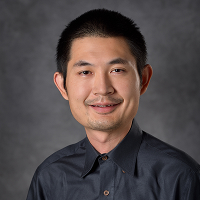 A headshot of Bin Gu smiling in a black dress shirt