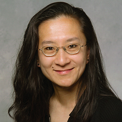 A headshot of Christina Chan smiling while wearing glasses a black top