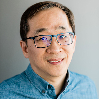 A headshot of Dohun Pyeon smiling wearing glasses and a blue dress shirt 