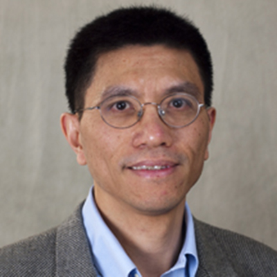 A headshot of Hua Xiao smiling wearing glasses and a gray blazer over a blue dress shirt