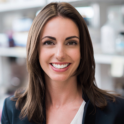 A headshot of Jamie Bernard smiling for a headshot wearing a black blazer with a white blouse