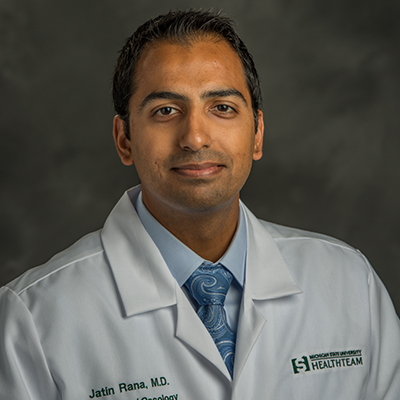 A headshot of Jatin Rana smiling wearing a white lab coat over a blue dress shirt and tie