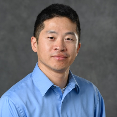 A headshot of Jinda Fan smiling while wearing a blue dress shirt