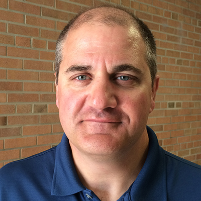 A headshot of John LaPres smiling wearing a dark blue polo