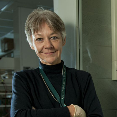 A headshot of Katheryn Meek smiling crossing her arms while wearing a black turtle neck