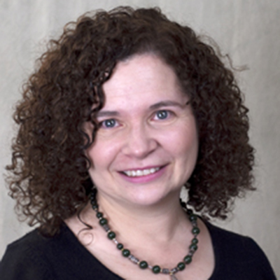 A headshot of Kathleen Gallo smiling while wearing a black top and black pearl necklace