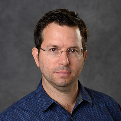 A headshot of Lorenzo Sempere wearing glasses and a dark navy blue dress shirt