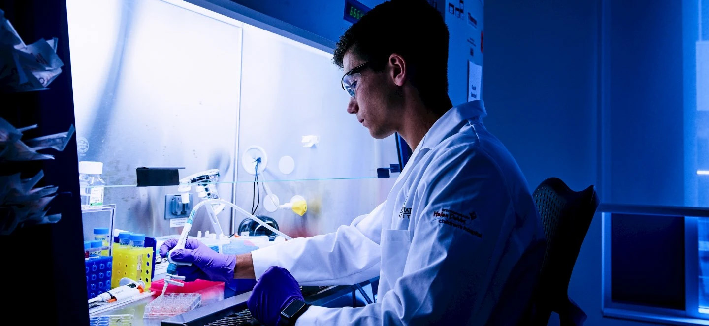 A person wearing a lab coat working inside a laboratory