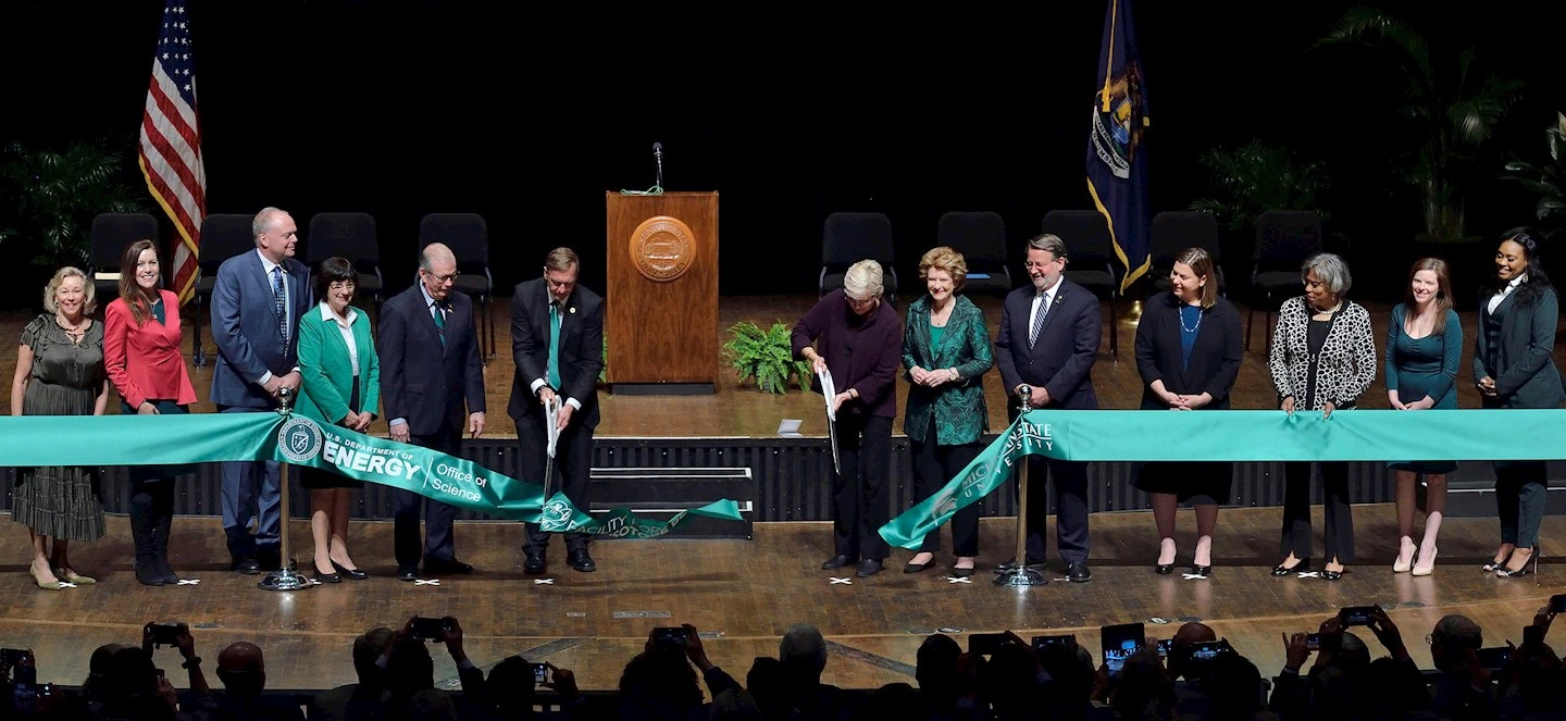 People cutting ribbon together on stage