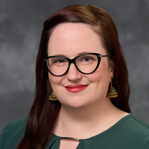A headshot of Ashly Westrick wearing glasses, hair down and green blouse. 