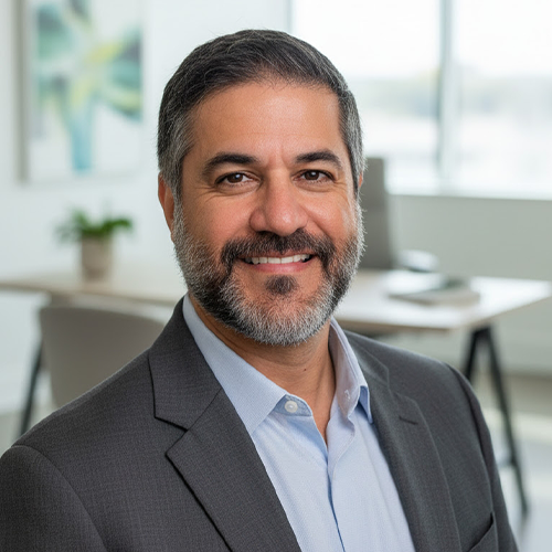 A headshot of Houtan Noushmehr wearing gray suit jacket with desk in background.