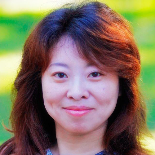 A headshot of Xiaoqun Dong with a green outdoor background. 