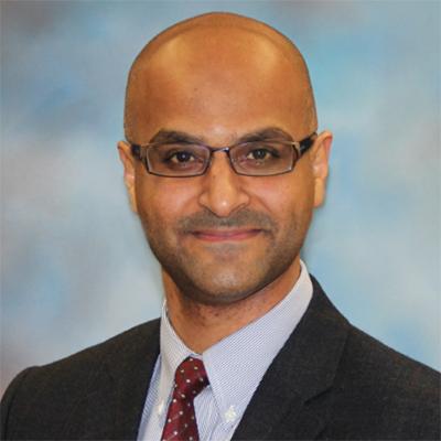A headshot of Yasser Aldhamen smiling in a suit