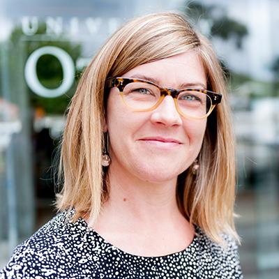 A headshot of Amber Pearson smiling wearing glasses and a black and white top