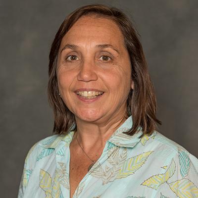 A headshot of Andrea Doseff smiling and wearing a blue top