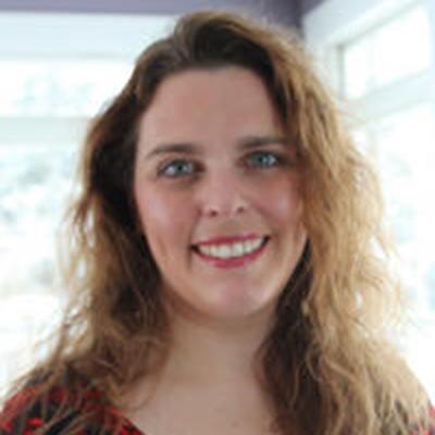 A headshot of Betsy Wasilevich smiling wearing a black and red top