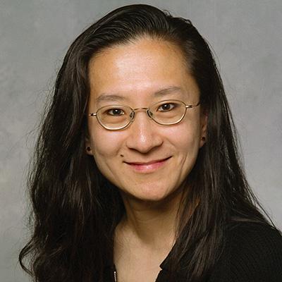 A headshot of Christina Chan smiling while wearing glasses a black top