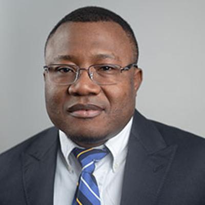 A headshot of David Todem wearing glasses, a blacker blazer over a white dress shirt, and a blue striped tie