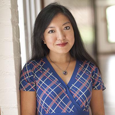 A headshot of Felicia Wu smiling wearing a blue plaid top and necklace