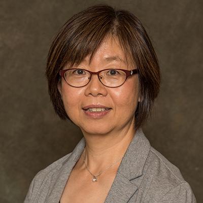 A headshot of Horng-Shiuann Wu smiling wearing glasses and a gray blazer with a necklace