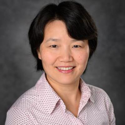 A headshot of Huirong Xie smiling wearing a pink and black polka dot dress shirt