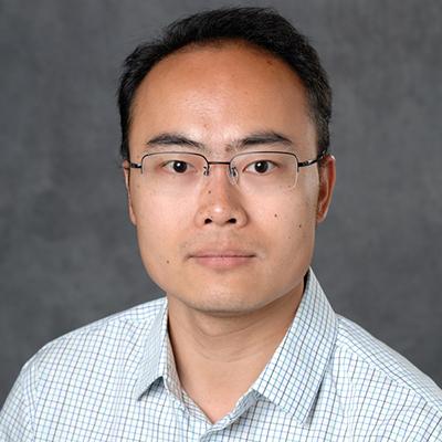 A headshot of Jianrong Wang wearing glasses with a plaid button up