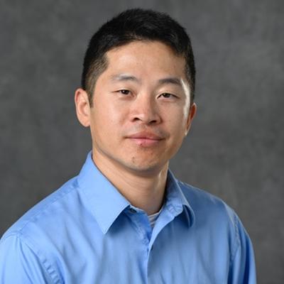 A headshot of Jinda Fan smiling while wearing a blue dress shirt