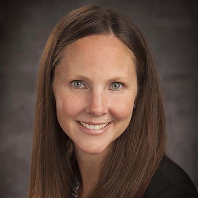 A headshot of Kelly Hirko smiling wearing a black top