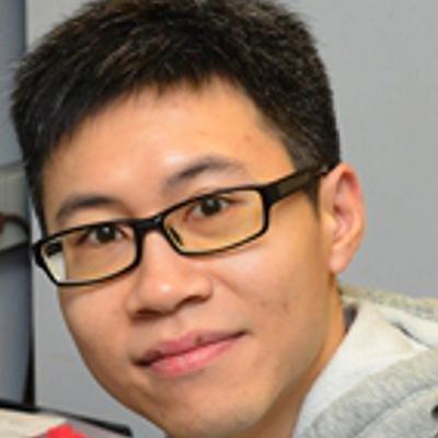 A headshot of Kin Sing Stephen Lee smiling wearing a gray hoodie and glasses
