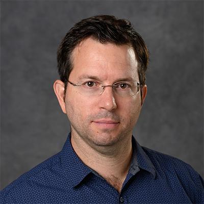 A headshot of Lorenzo Sempere wearing glasses and a dark navy blue dress shirt