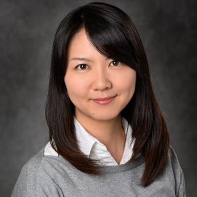 A headshot of Masako Harada smiling wearing a gray sweater over a white collar shirt